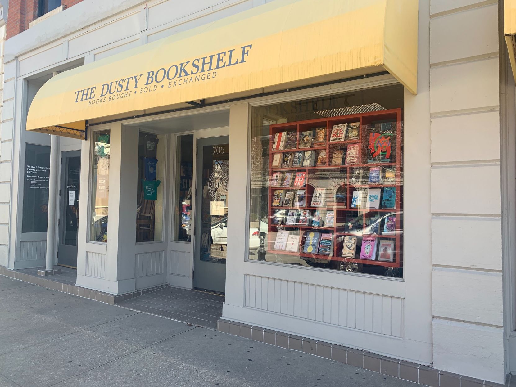 Books fill the shelves in the window under the awning at The Dusty Bookshelf